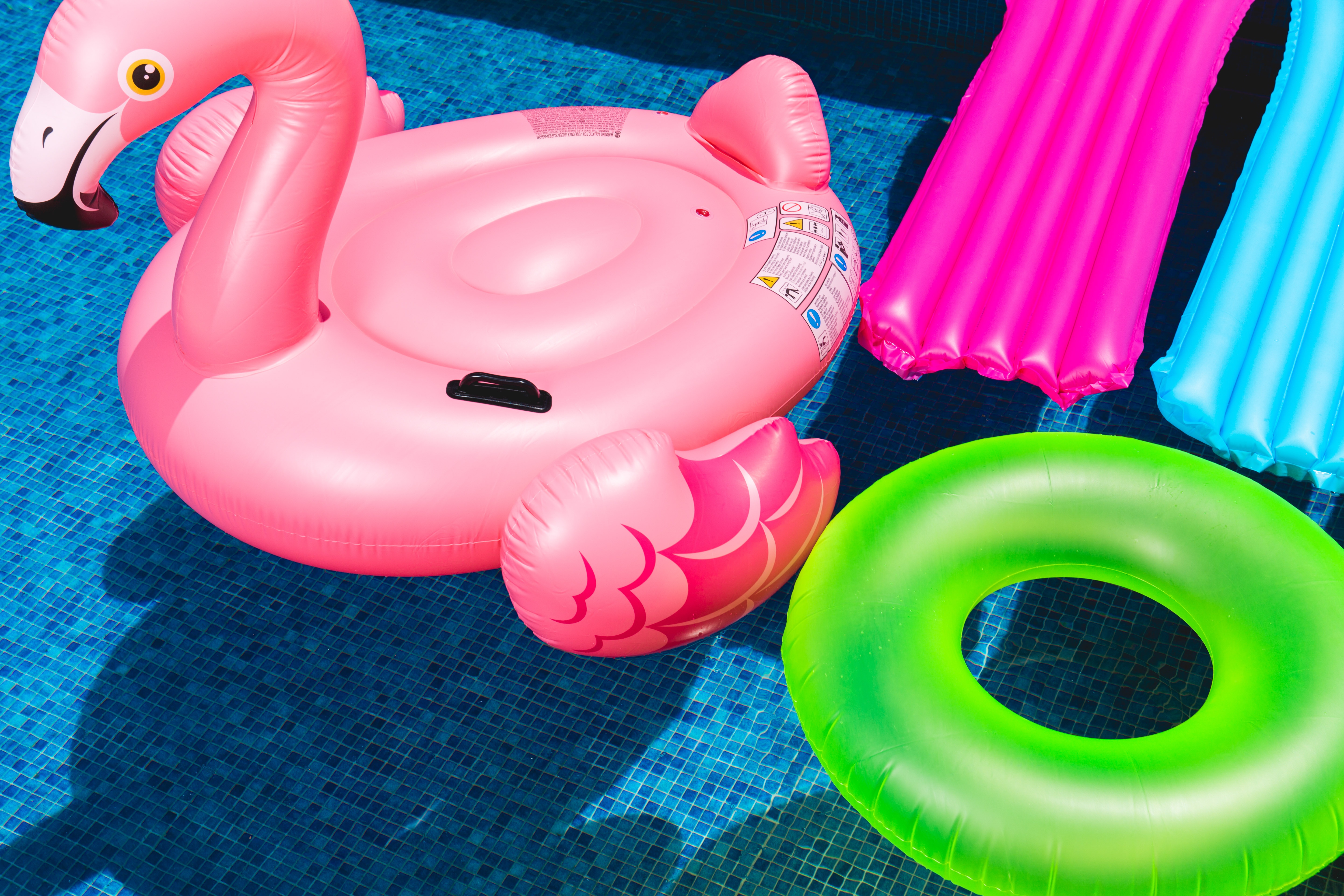 Outdoor water toys. Variety of pool float toys. Pink Flamingo and two beds one blue one pink.